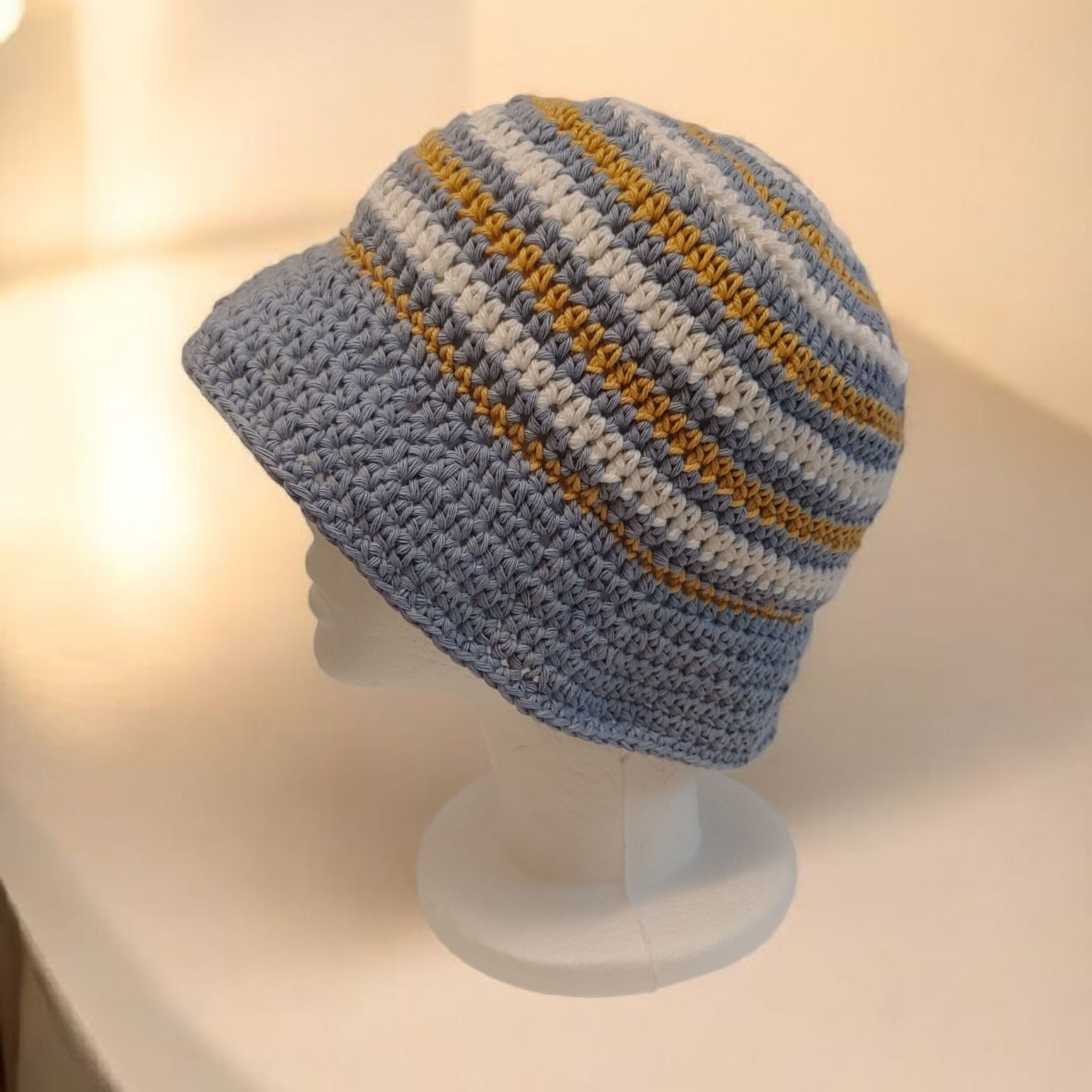 Crochet blue bucket hat with yellow and white stripe.