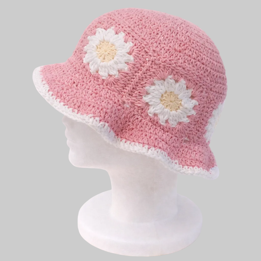 Handmade blush pink crochet bucket hat with white daisy flowers and soft brim, crafted from cotton yarn by Green Stitch.